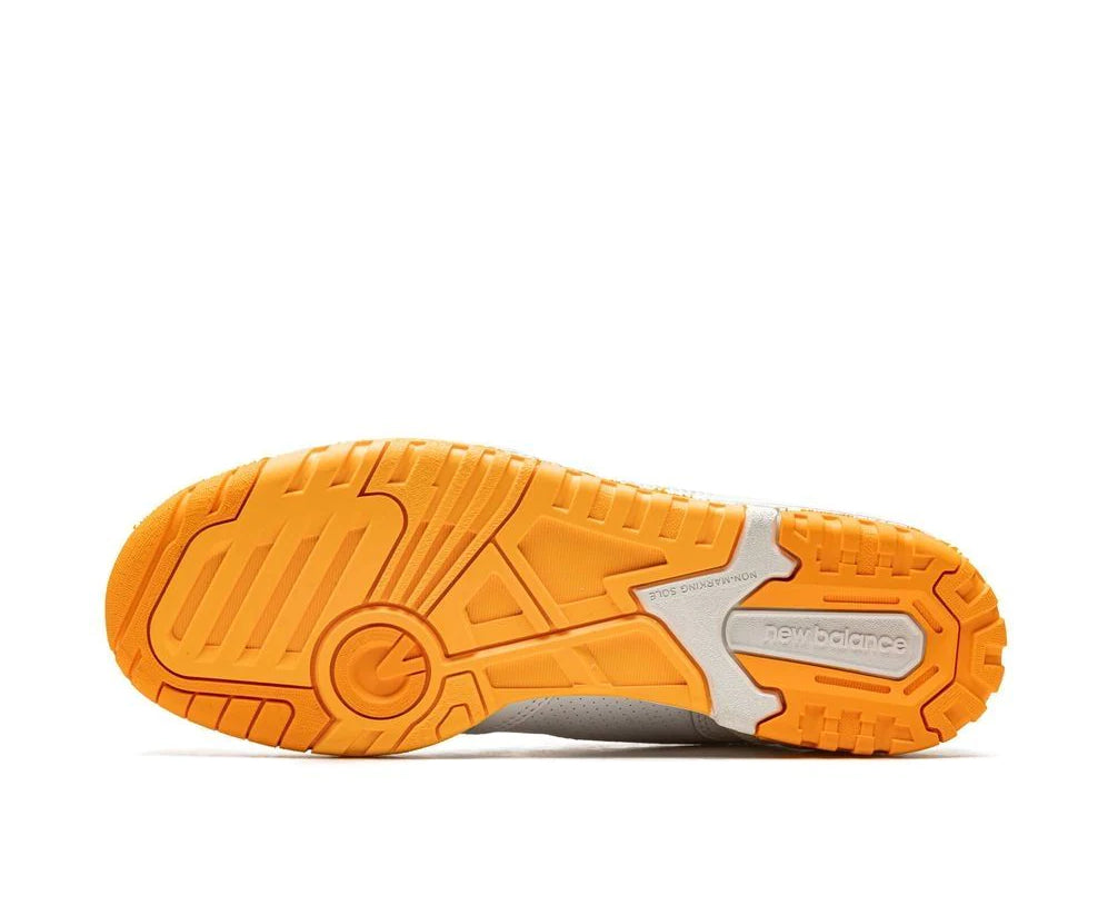 A white leather New Balance basketball shoe with orange and indigo accents.