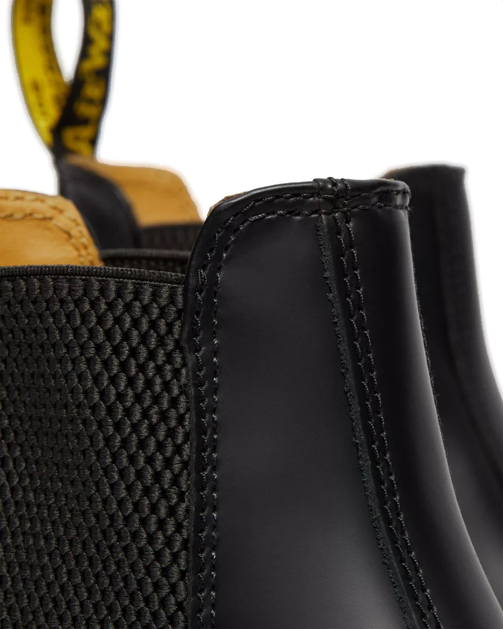 Detail shot of a pair of mid-ankle Dr. Martens black leather chelsea boots.