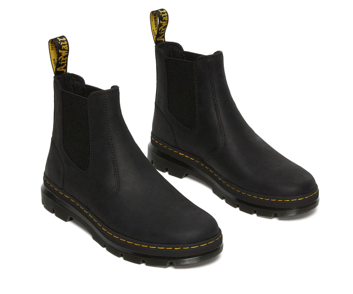 A black, softened leather chelsea boot from Dr. Martens with yellow accent stitching.