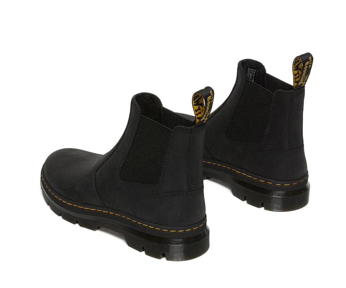 A black, softened leather chelsea boot from Dr. Martens with yellow accent stitching.