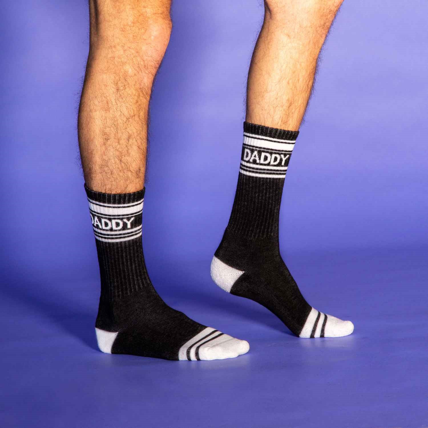 A pair of black and white crew socks that read "daddy."